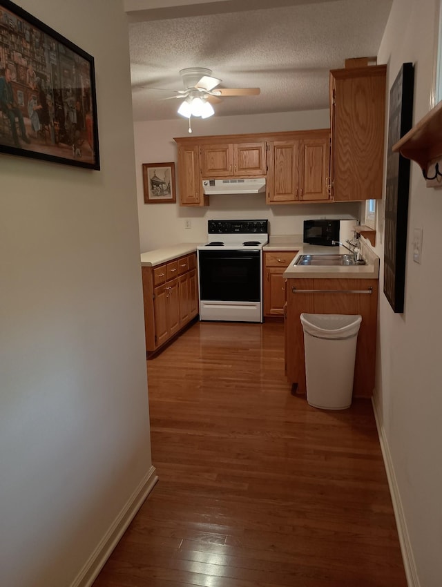 kitchen featuring a sink, baseboards, electric range oven, and wood finished floors