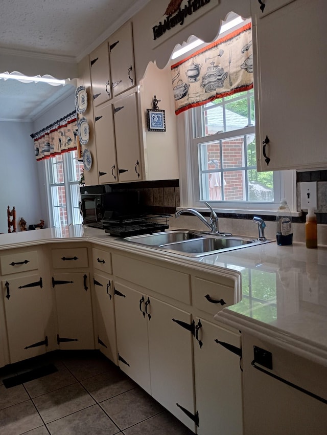 kitchen with crown molding, white cabinets, a sink, tile patterned flooring, and light countertops