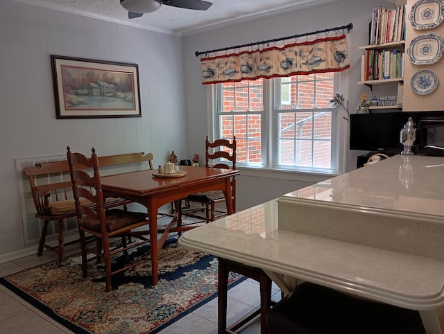 tiled dining space featuring ornamental molding, a ceiling fan, and a textured ceiling