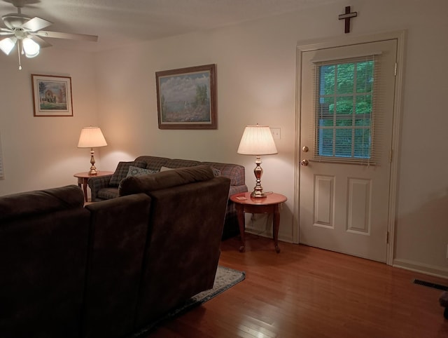 living area featuring a ceiling fan, baseboards, visible vents, and wood finished floors