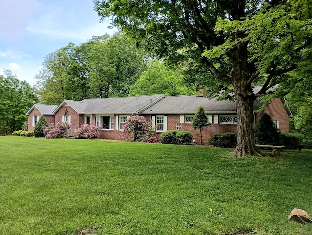 single story home with brick siding, a chimney, and a front yard