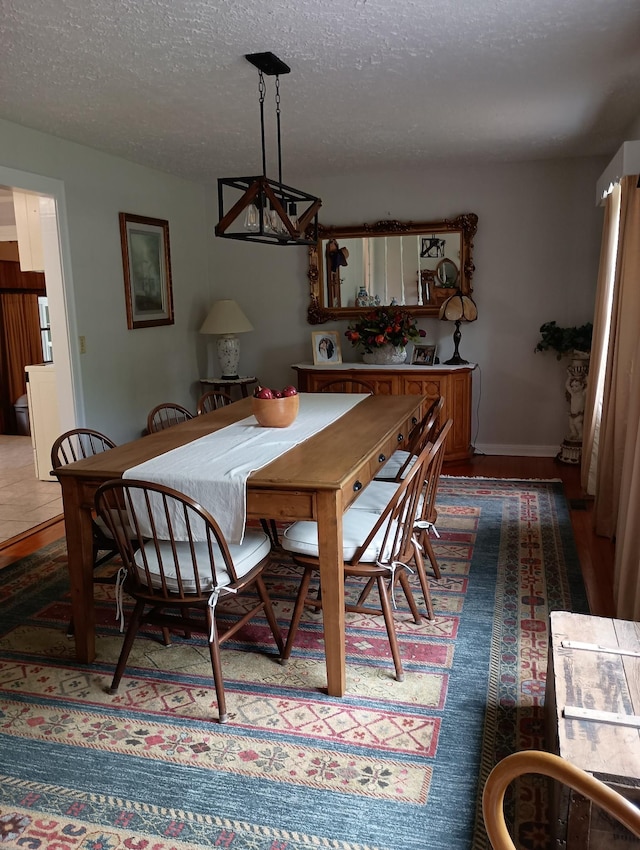 dining area featuring baseboards, a textured ceiling, and a chandelier