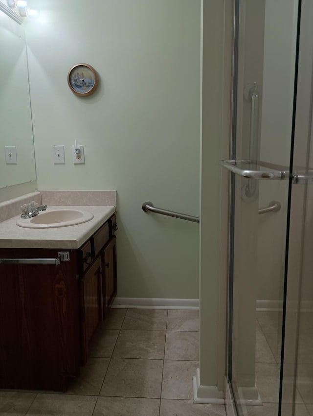 bathroom with vanity, tile patterned flooring, baseboards, and a stall shower