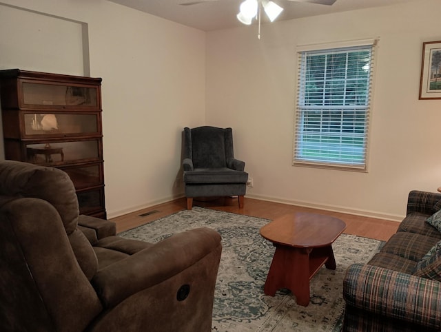 living area featuring ceiling fan, plenty of natural light, baseboards, wood finished floors, and visible vents