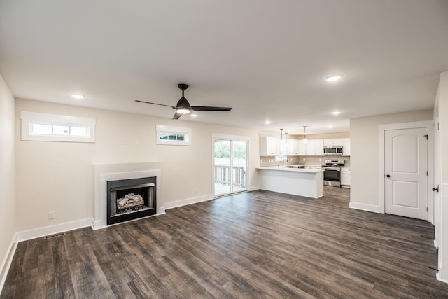 unfurnished living room featuring a ceiling fan, recessed lighting, a sink, and dark wood finished floors