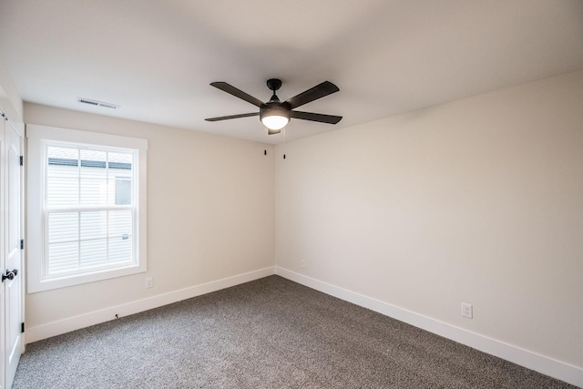 unfurnished room with baseboards, ceiling fan, dark colored carpet, and visible vents