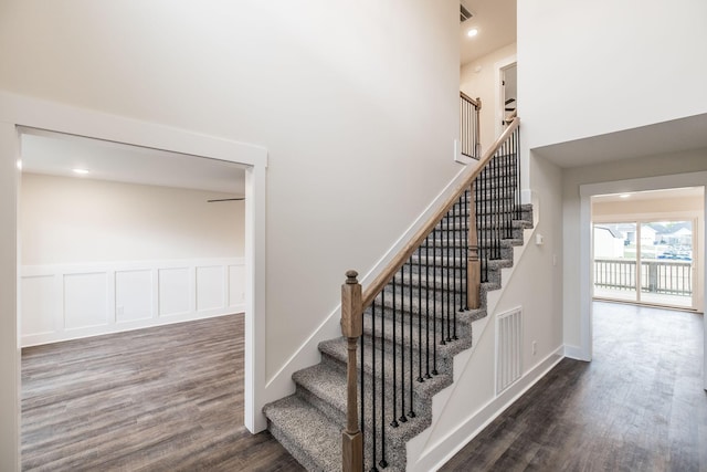 stairs featuring visible vents, a high ceiling, wood finished floors, and recessed lighting