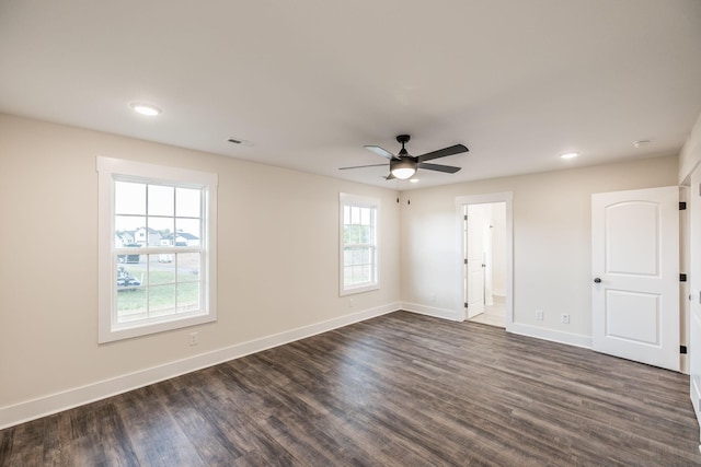 empty room with baseboards, ceiling fan, dark wood finished floors, and visible vents