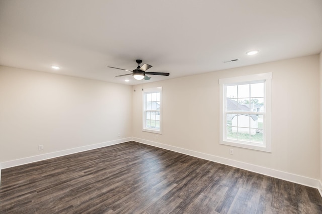 empty room featuring a ceiling fan, baseboards, dark wood finished floors, and visible vents