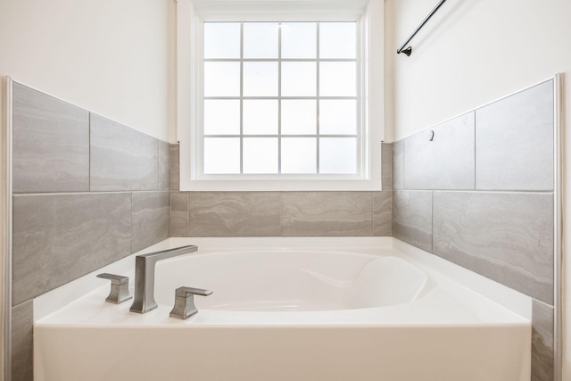 bathroom with a garden tub and tile walls