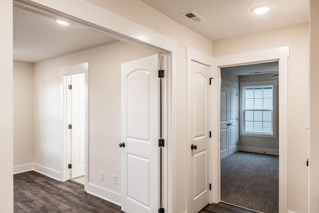 corridor with baseboards, visible vents, and dark wood-style floors