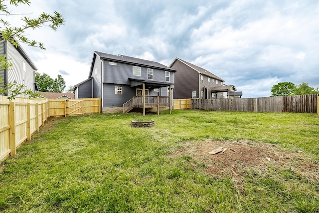 back of house with a fenced backyard, an outdoor fire pit, a wooden deck, and a yard