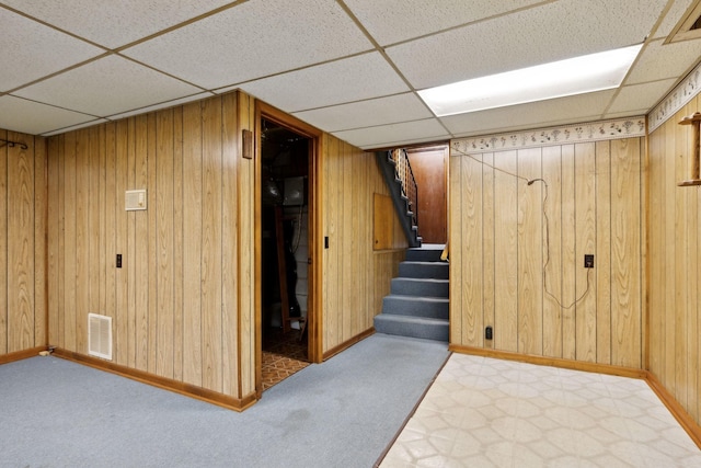 finished below grade area featuring stairway, carpet flooring, a paneled ceiling, and visible vents