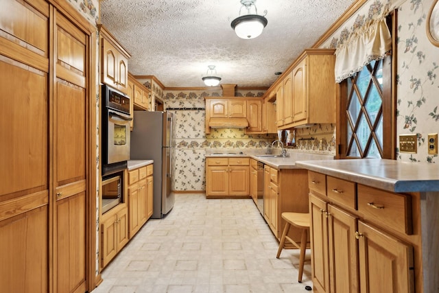 kitchen featuring crown molding, stainless steel appliances, wallpapered walls, and a sink