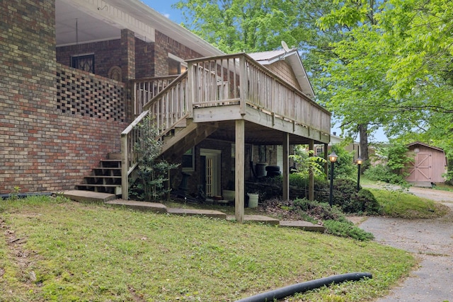back of house with a deck, a lawn, a storage shed, an outbuilding, and stairway