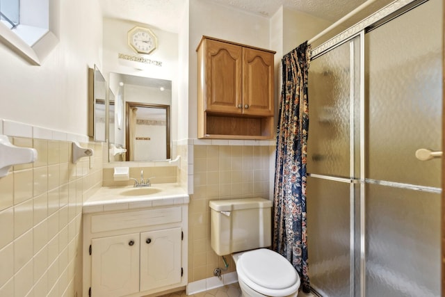 full bath with a textured ceiling, tile walls, a shower stall, vanity, and toilet