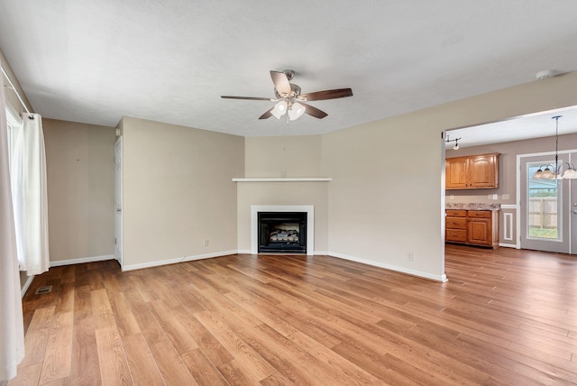 210 Edgewood Dr, Hohenwald, TN 38462 - unfurnished living room featuring baseboards, ceiling fan, light wood-style flooring, and a fireplace