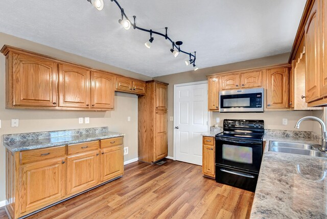 210 Edgewood Dr, Hohenwald, TN 38462 - kitchen featuring black electric range oven, a sink, baseboards, stainless steel microwave, and light wood-style flooring
