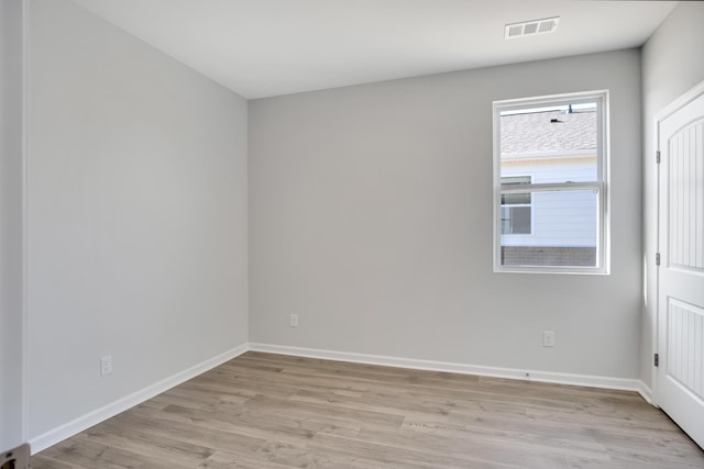 spare room with baseboards, light wood finished floors, and visible vents