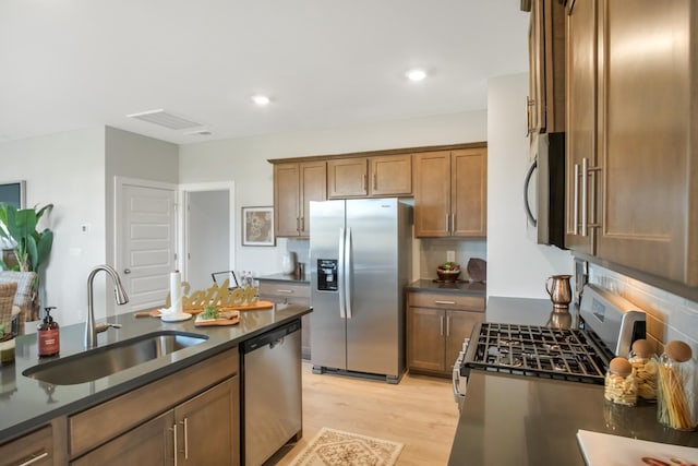 kitchen with stainless steel appliances, dark countertops, decorative backsplash, and a sink