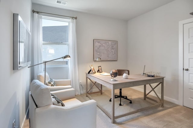 office area with visible vents, baseboards, and light carpet