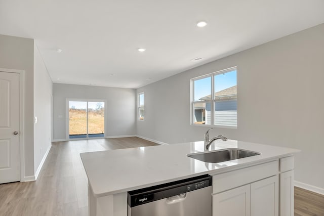 kitchen with stainless steel dishwasher, plenty of natural light, a sink, and a kitchen island with sink
