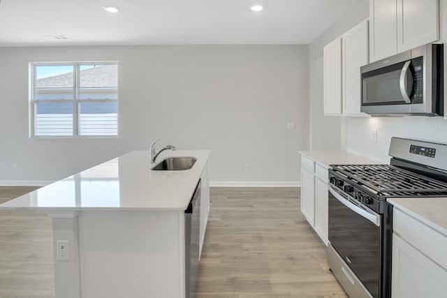 kitchen with baseboards, appliances with stainless steel finishes, a sink, and light wood-type flooring