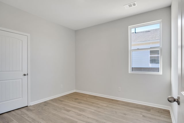 empty room with baseboards, visible vents, and light wood-type flooring