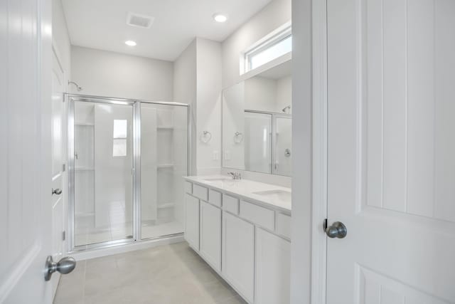 bathroom featuring a sink, double vanity, tile patterned floors, a shower stall, and visible vents