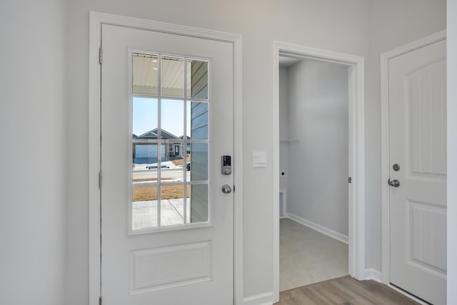 doorway with baseboards and wood finished floors