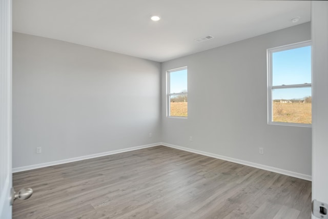 empty room featuring baseboards, light wood-style flooring, and visible vents