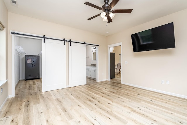 1317 Halls Mill Rd, Unionville, TN 37180 - unfurnished living room featuring ceiling fan, visible vents, a barn door, baseboards, and light wood-style flooring