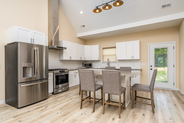 1317 Halls Mill Rd, Unionville, TN 37180 - kitchen featuring a breakfast bar area, visible vents, appliances with stainless steel finishes, light wood-style floors, and wall chimney exhaust hood
