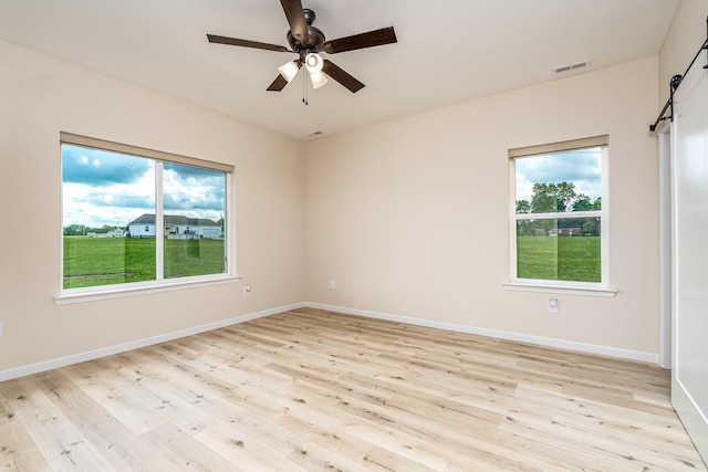 1317 Halls Mill Rd, Unionville, TN 37180 - unfurnished room featuring visible vents, baseboards, a barn door, a ceiling fan, and light wood finished floors
