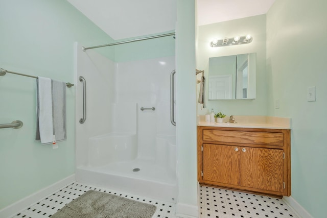 full bathroom with vanity, baseboards, tile patterned flooring, and walk in shower