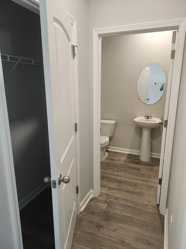 bathroom featuring baseboards, a sink, wood finished floors, and toilet