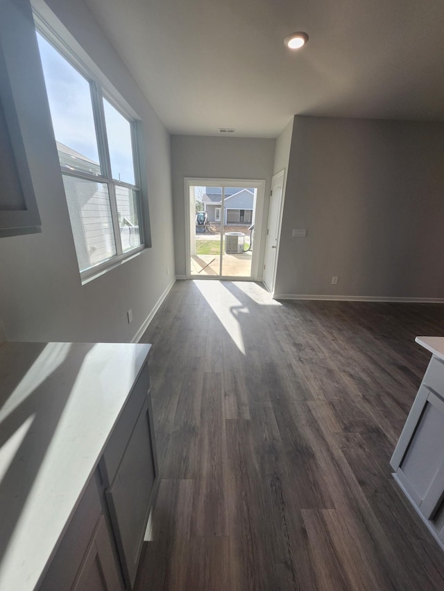 unfurnished living room with recessed lighting, baseboards, and dark wood finished floors