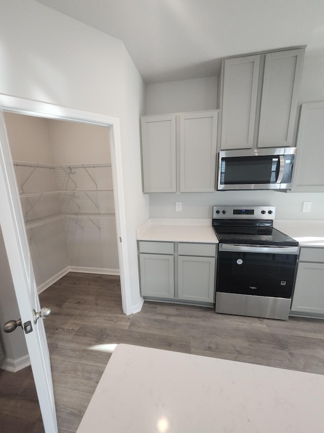 kitchen featuring appliances with stainless steel finishes, light countertops, gray cabinets, baseboards, and wood finished floors