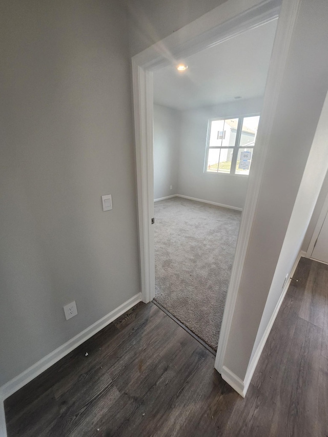 spare room featuring baseboards, carpet, and wood finished floors