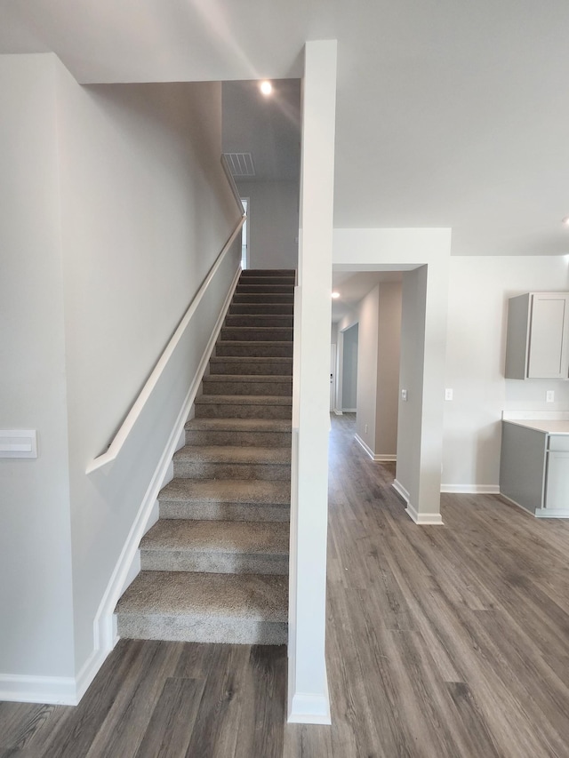 staircase with recessed lighting, baseboards, visible vents, and wood finished floors