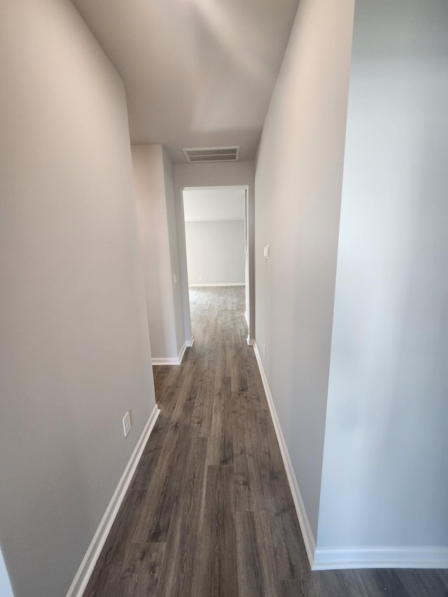 corridor with baseboards, dark wood finished floors, and visible vents