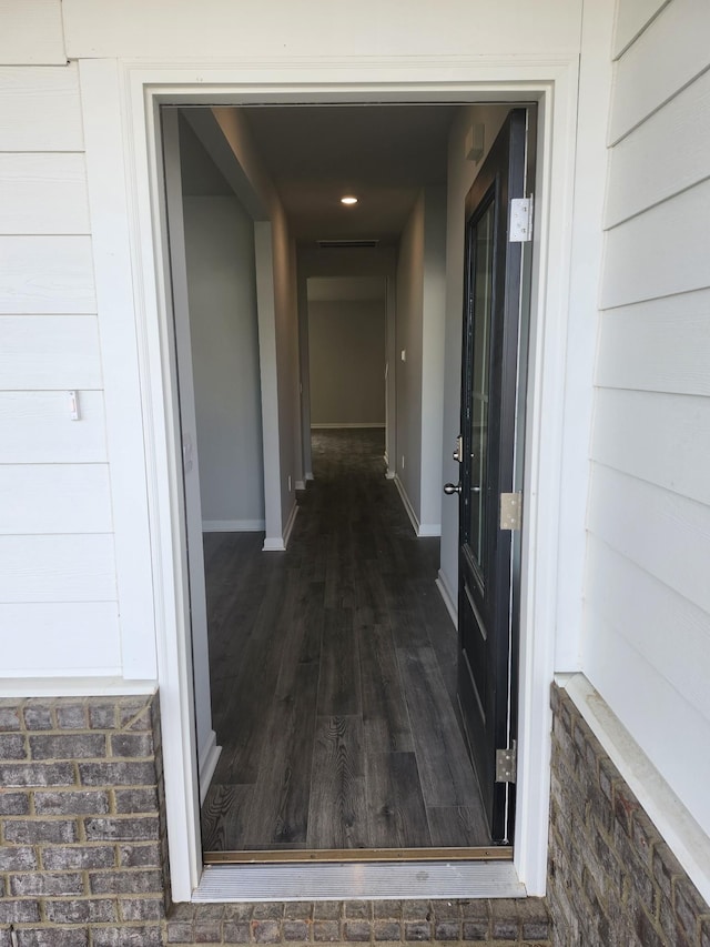 hallway featuring baseboards and dark wood-style flooring