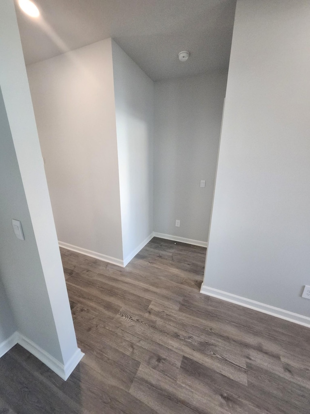 unfurnished room with baseboards and dark wood-style floors