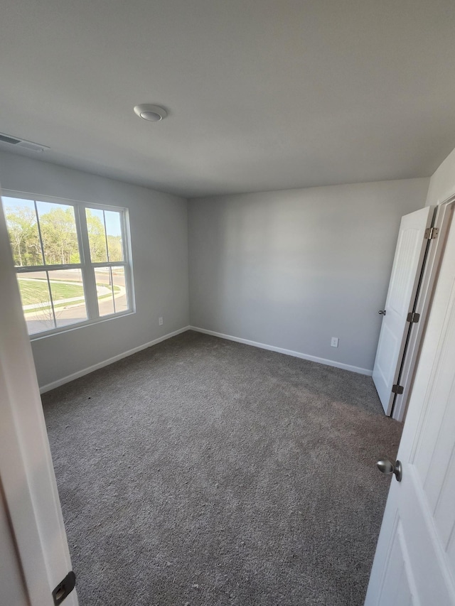 carpeted empty room featuring baseboards and visible vents