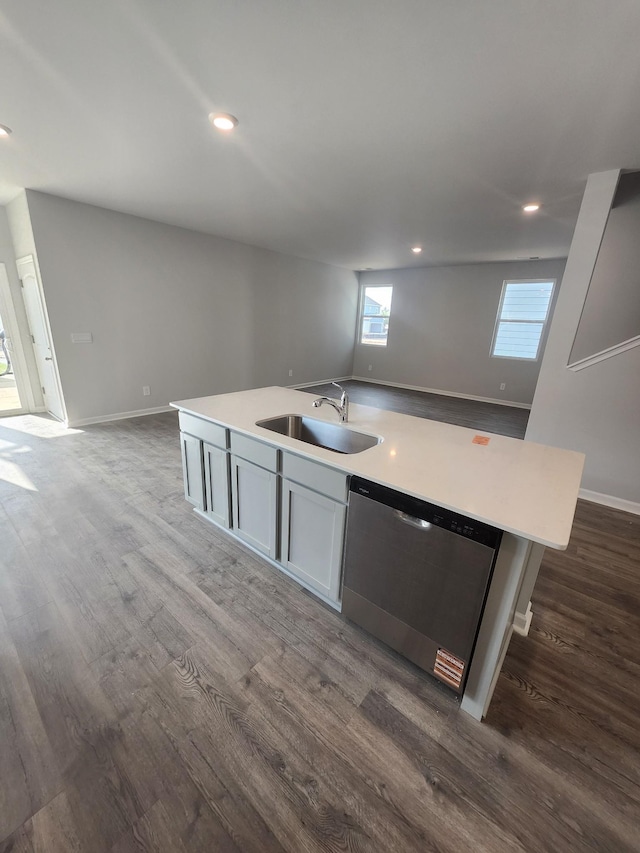 kitchen with stainless steel dishwasher, open floor plan, a sink, and dark wood-type flooring