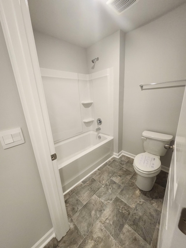 bathroom featuring toilet, stone finish floor, baseboards,  shower combination, and visible vents