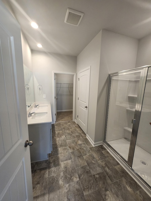 full bathroom with vanity, visible vents, a walk in closet, and a stall shower