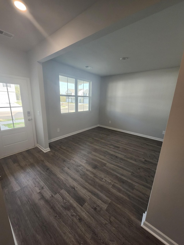 unfurnished room featuring visible vents, dark wood finished floors, baseboards, and a wealth of natural light