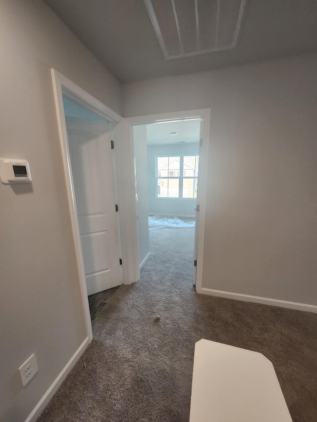 hallway featuring carpet floors, baseboards, and visible vents