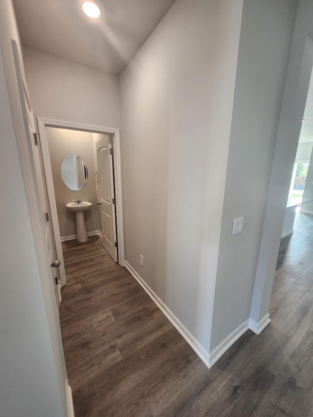 corridor featuring baseboards and dark wood finished floors